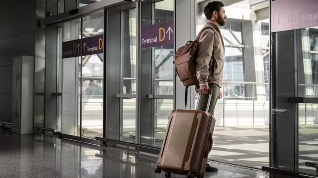 Homem com mochila e mala de viagem no aeroporto