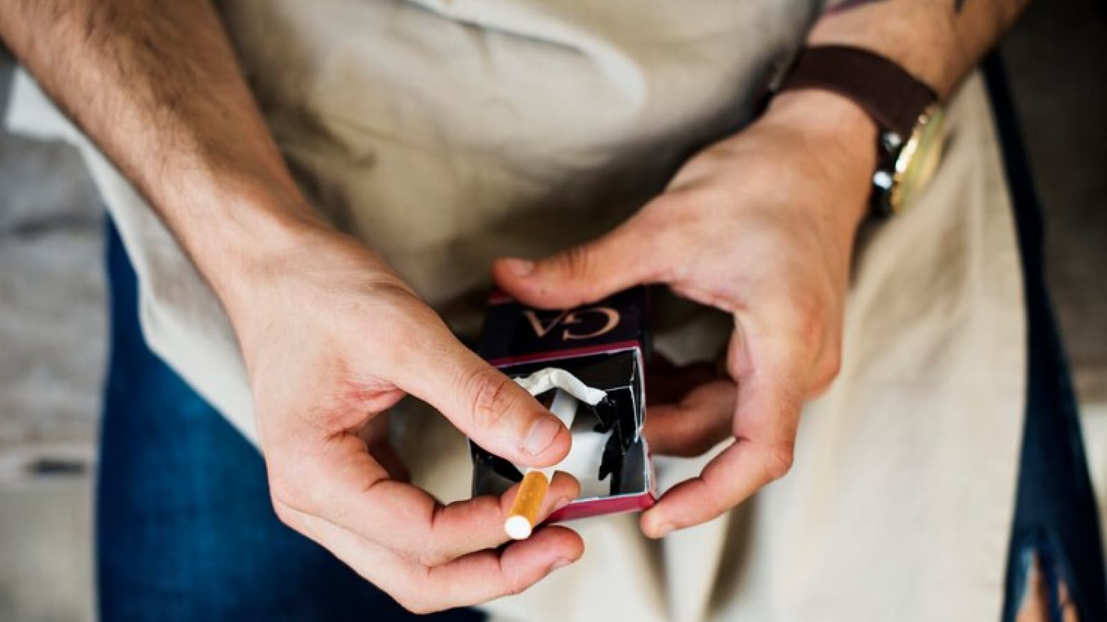 Homem segurando caixa de cigarros