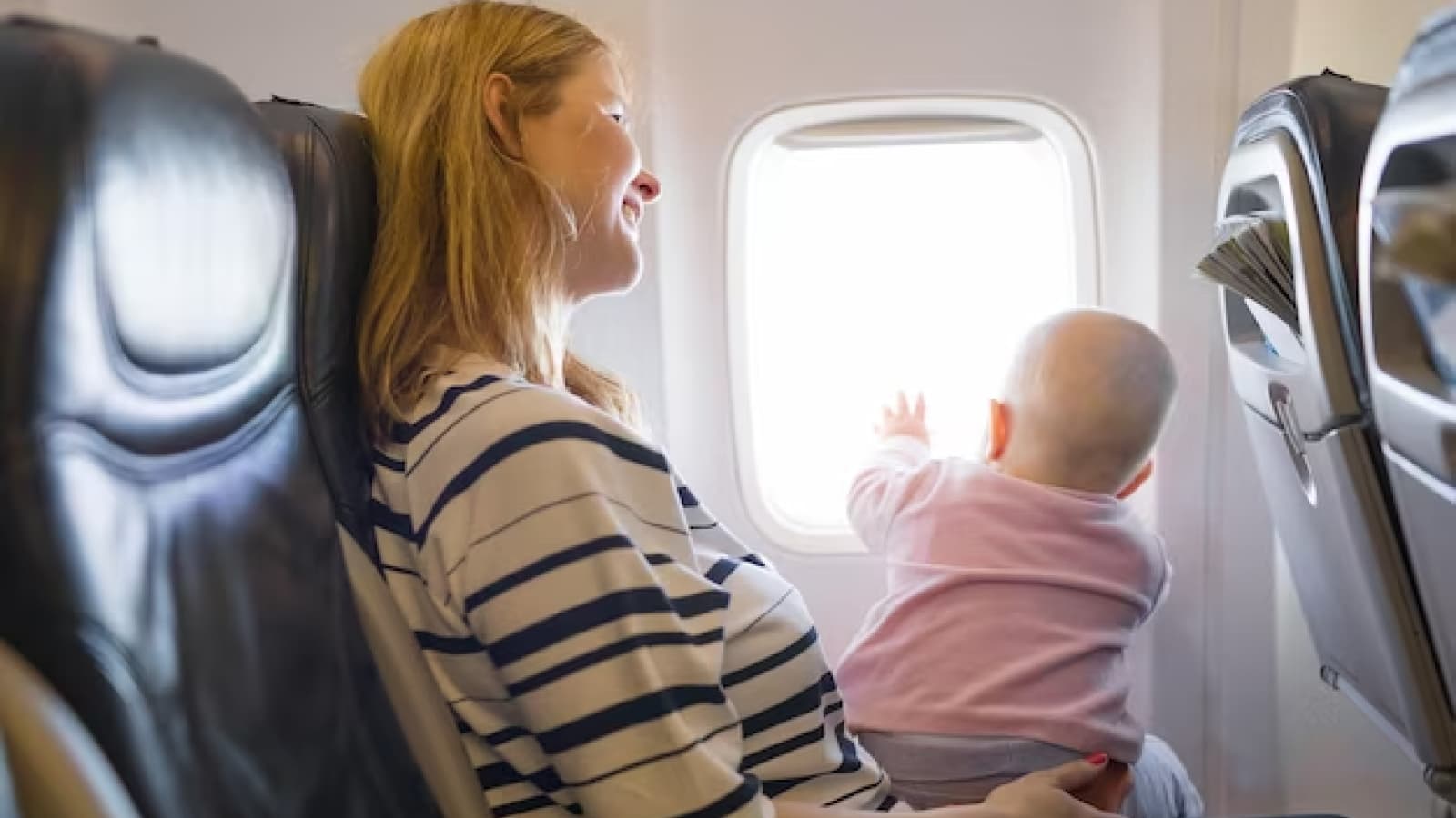 Mulher com bebê na janela de avião