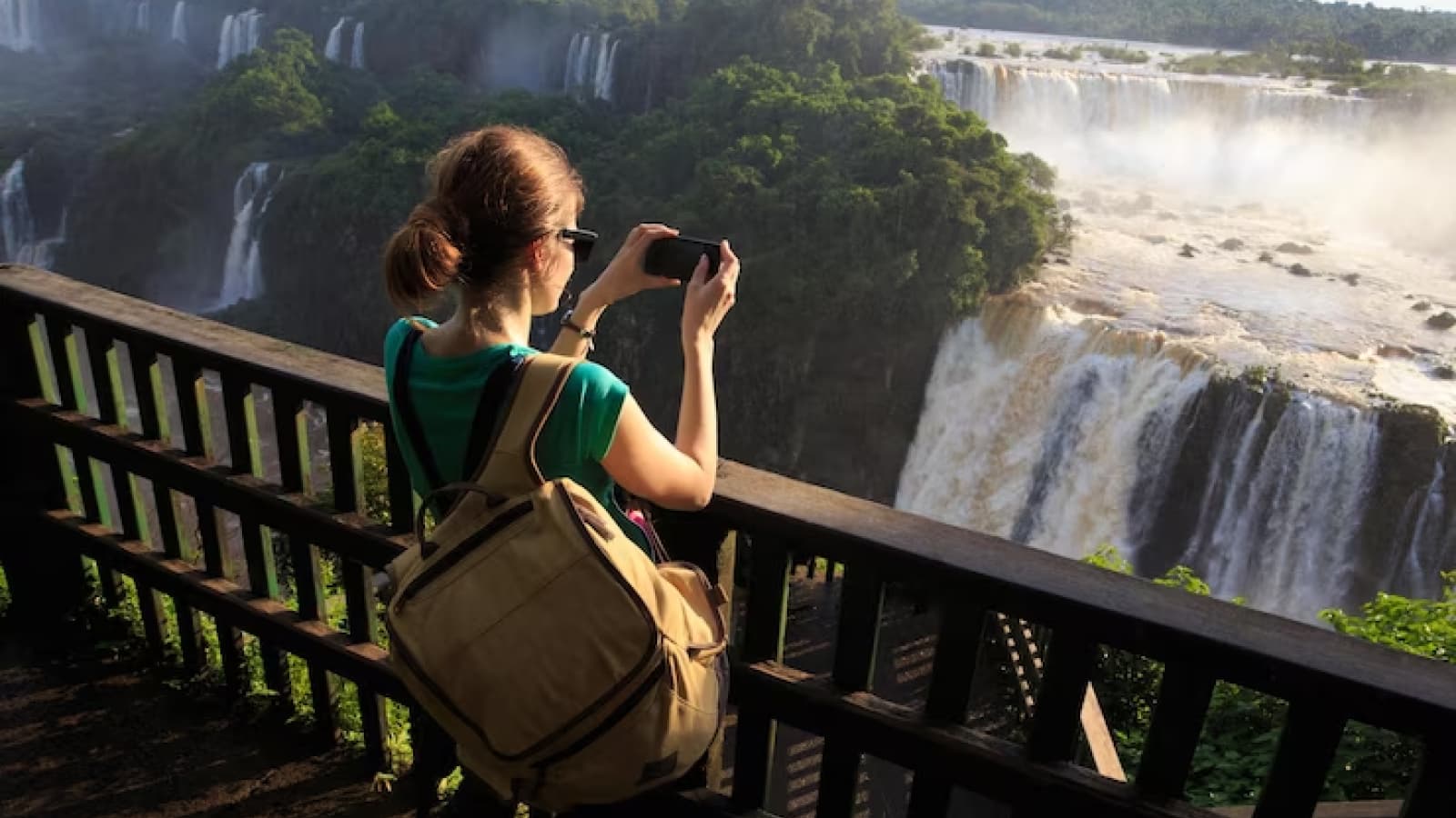 Mulher com mochila tirando foto nas Cataratas do Iguaçu