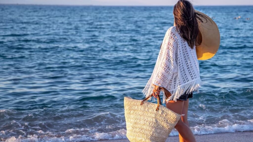 Mulher de costas na praia com saída de praia e bolsa de praia