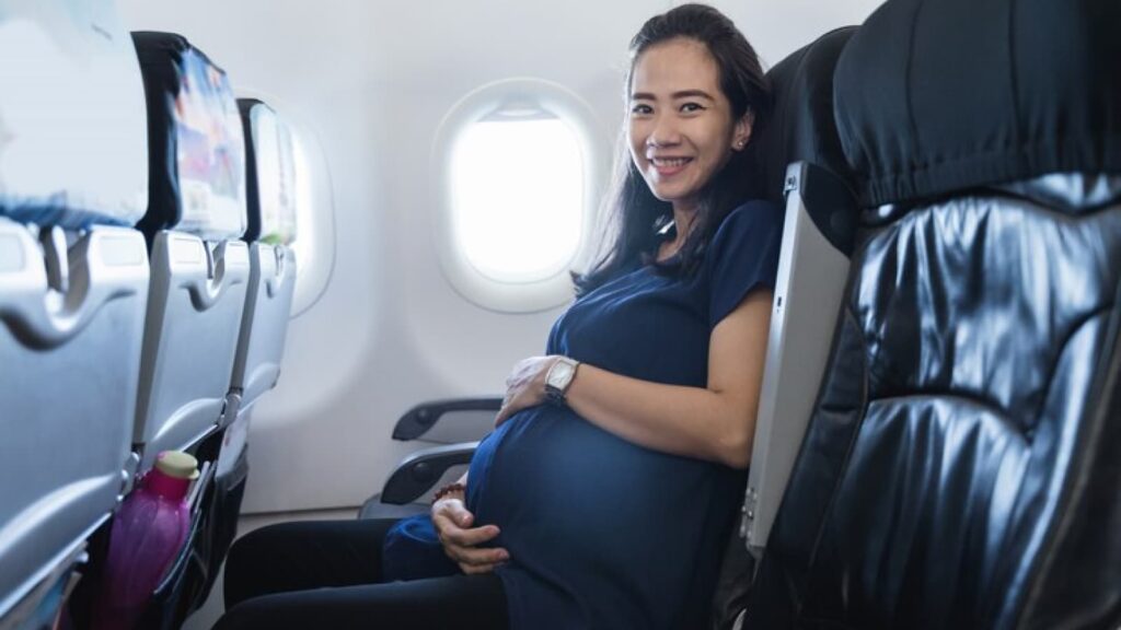 Mulher grávida sorrindo em assento de avião