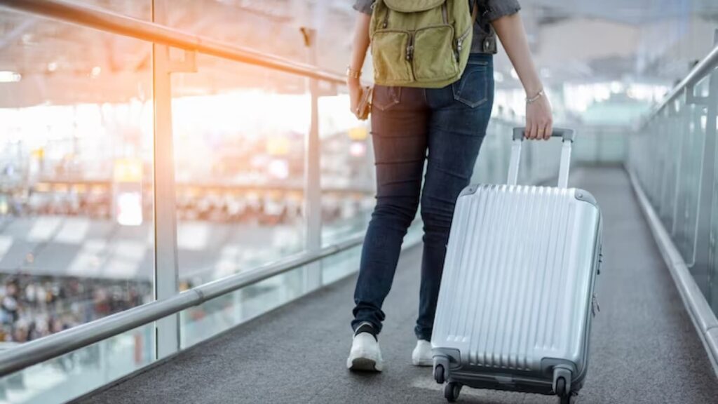 Pessoa com mochila e mala de viagem em aeroporto